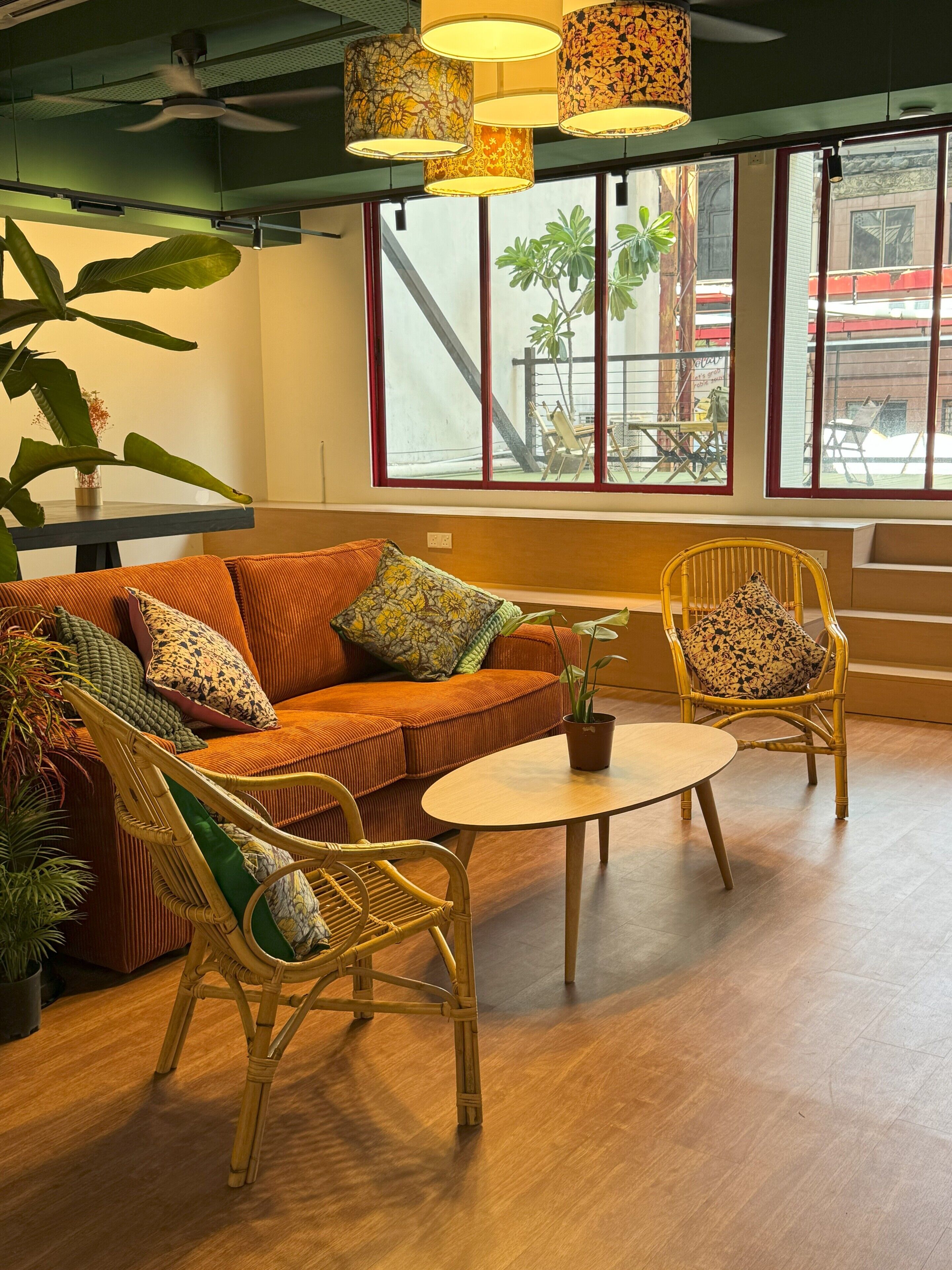 Une pièce confortable avec un canapé, deux fauteuils, une petite table et de grandes fenêtres donnant sur l’extérieur.
