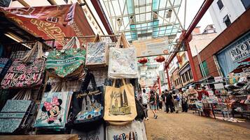 A bustling market street with various stalls selling bags and souvenirs.