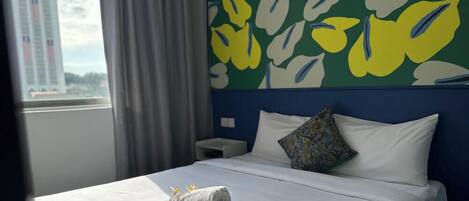 A hotel room with a bed, a nightstand, a pillow, and a window with curtains.