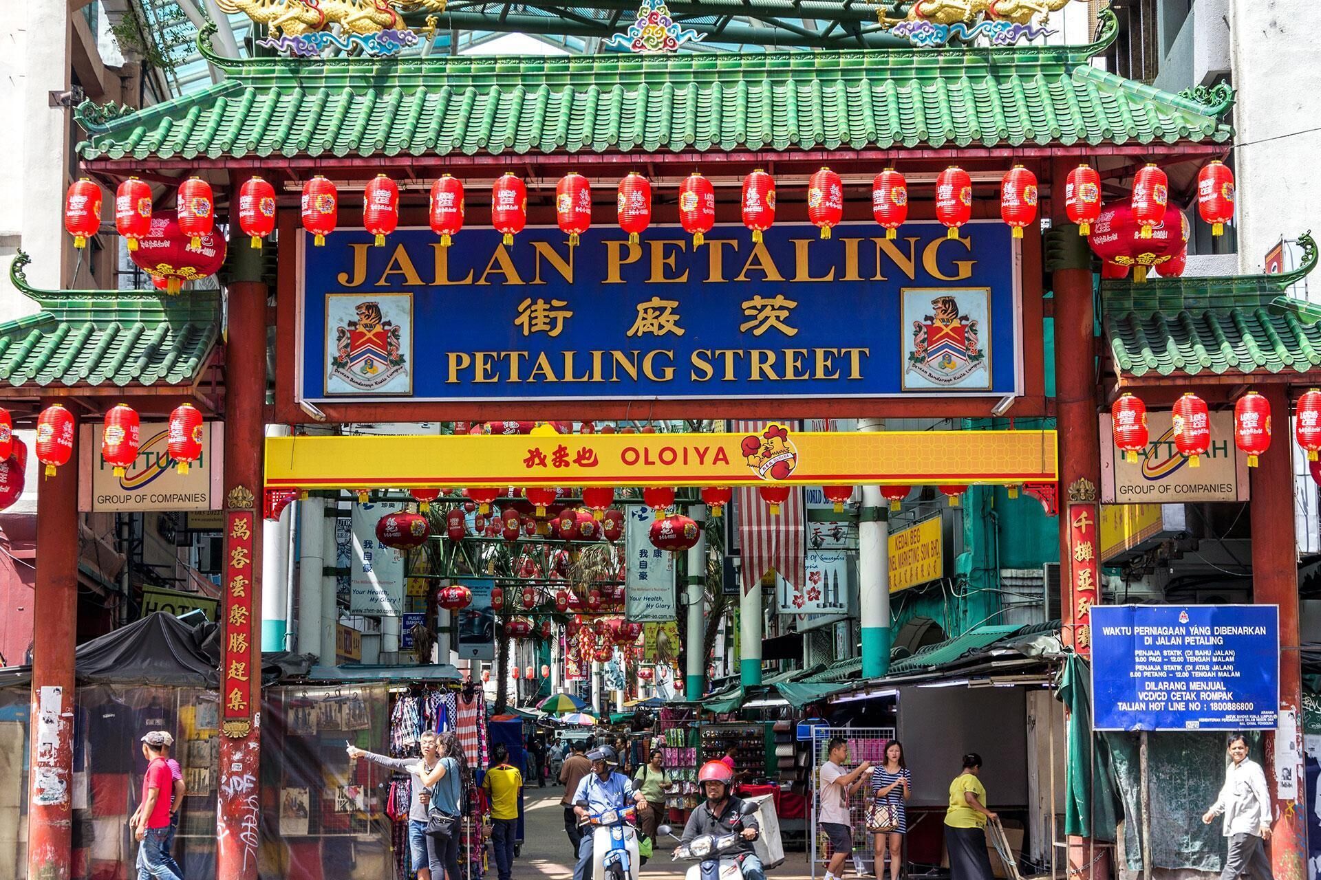 A street sign for Jalan Petaling Street with traditional Chinese architecture and red lanterns.