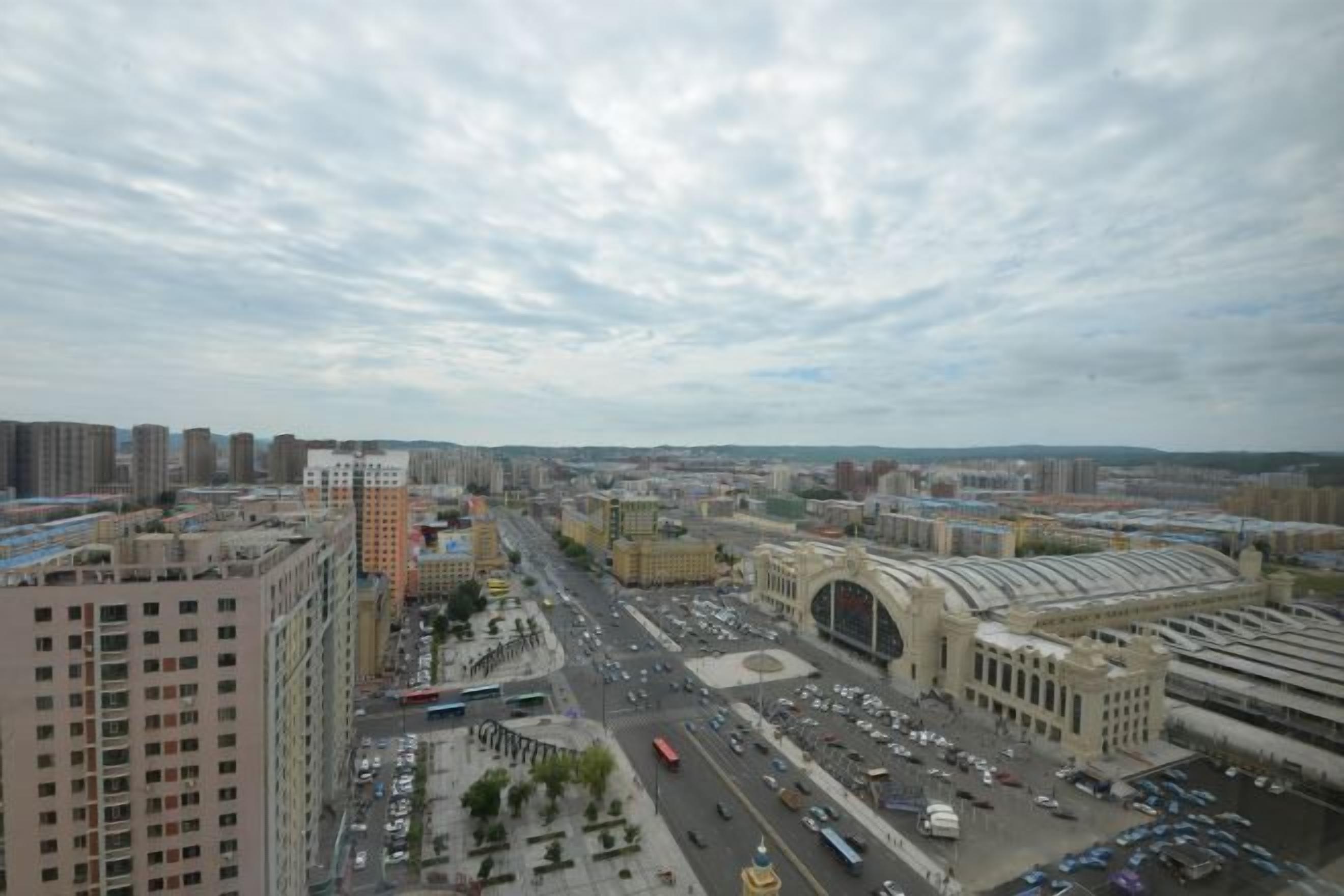 A cityscape with a prominent train station and surrounding high-rise buildings.
