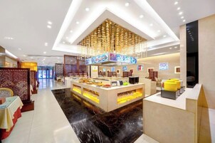 Un moderno vestíbulo de hotel con un mostrador de recepción central, una araña y un suelo de mármol negro.