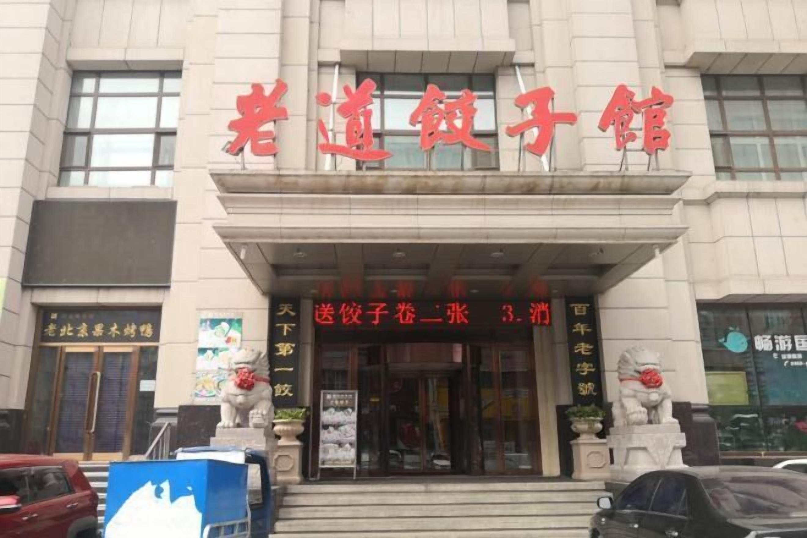 A building with a sign that reads "老道饺子馆" and a smaller sign below it that says "  送饺子一张 3.门".