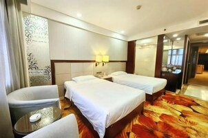 A hotel room with two beds, a small table, a chair, and a mirror.