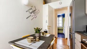 Eine moderne Küche mit Esstisch, Stühlen und einem Kühlschrank.