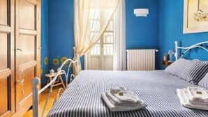 Ein Schlafzimmer mit Bett, Kleiderschrank, Heizkörper und einem Fenster mit Vorhängen.
