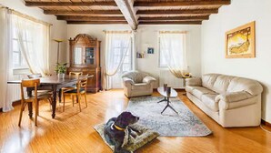 Ein geräumiges Wohnzimmer mit Holzboden, einem Esstisch, einer Couch und einem Hund.