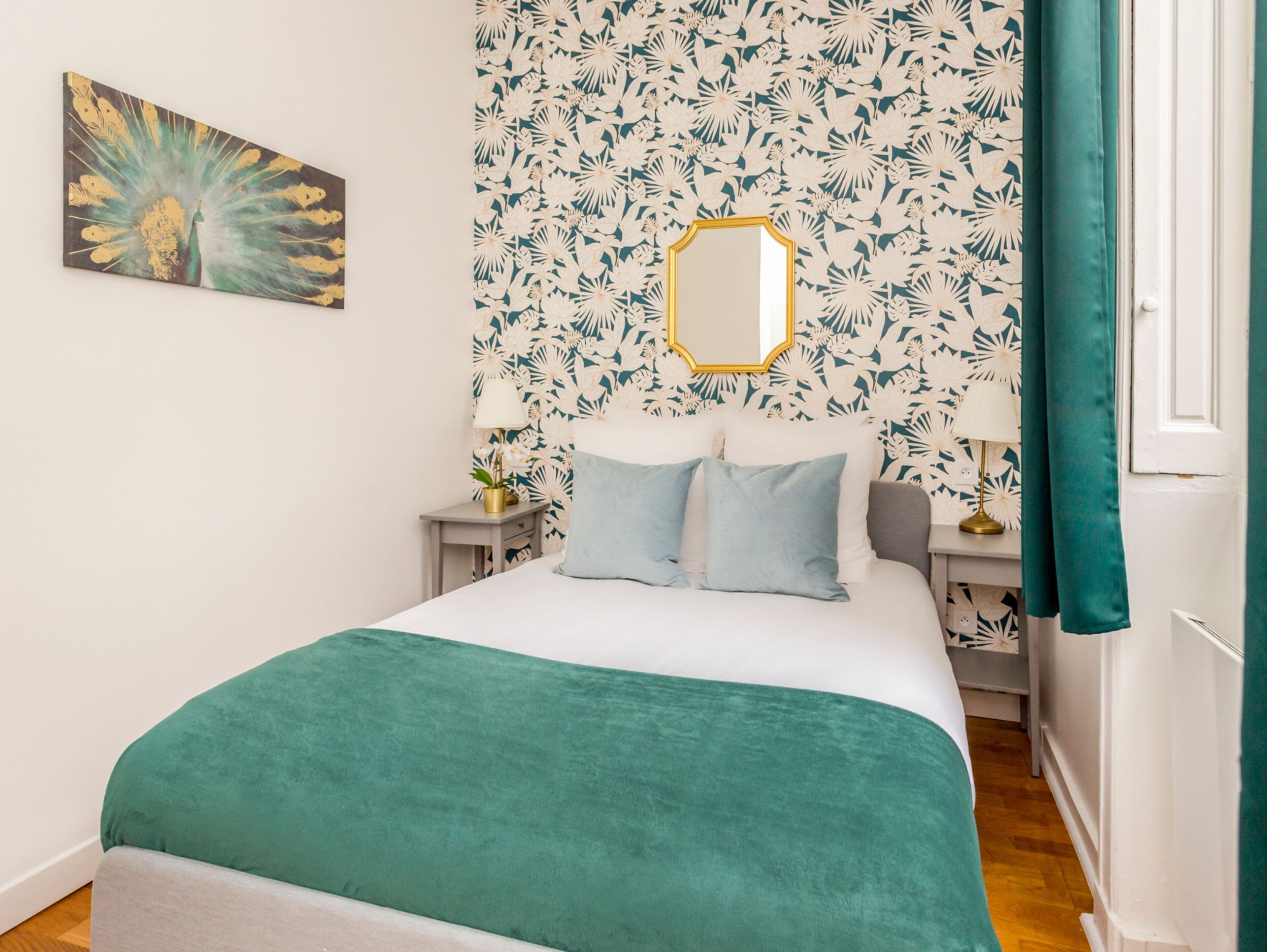 A bedroom with a bed, a mirror, and a floral wallpaper.