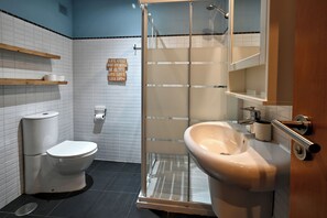 Une salle de bain avec des toilettes, un lavabo et une douche.