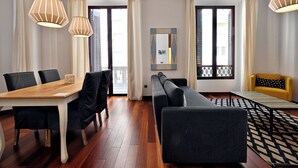 Ein modernes Wohnzimmer mit einem Holzesstisch, schwarzen Stühlen, einem grauen Sofa, einem gelben Sessel und einem gemusterten Teppich.