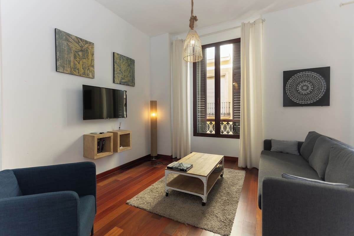 Ein Wohnzimmer mit einer Couch, einem Couchtisch, einem Fernseher und Kunstwerken an den Wänden.