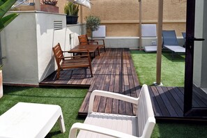 Une terrasse avec des meubles en bois, une table blanche et une petite chaise blanche.