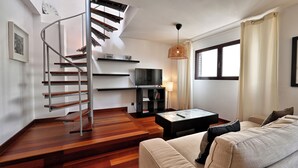 Ein modernes Wohnzimmer mit Treppe, einer Couch, einem Fernseher und einer Lampe.