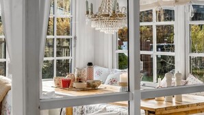 Une pièce chaleureuse avec une table en bois, des coussins à motifs floraux et un lustre.