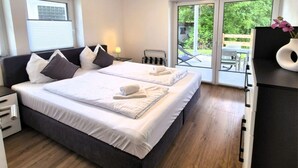 A double bed with white linens, a dark headboard, and a side table with a lamp. - Moderne Ferienwohnung in Winterberg (Winterberg)