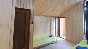 A wooden cabin with two beds, a wooden door, and a large window.