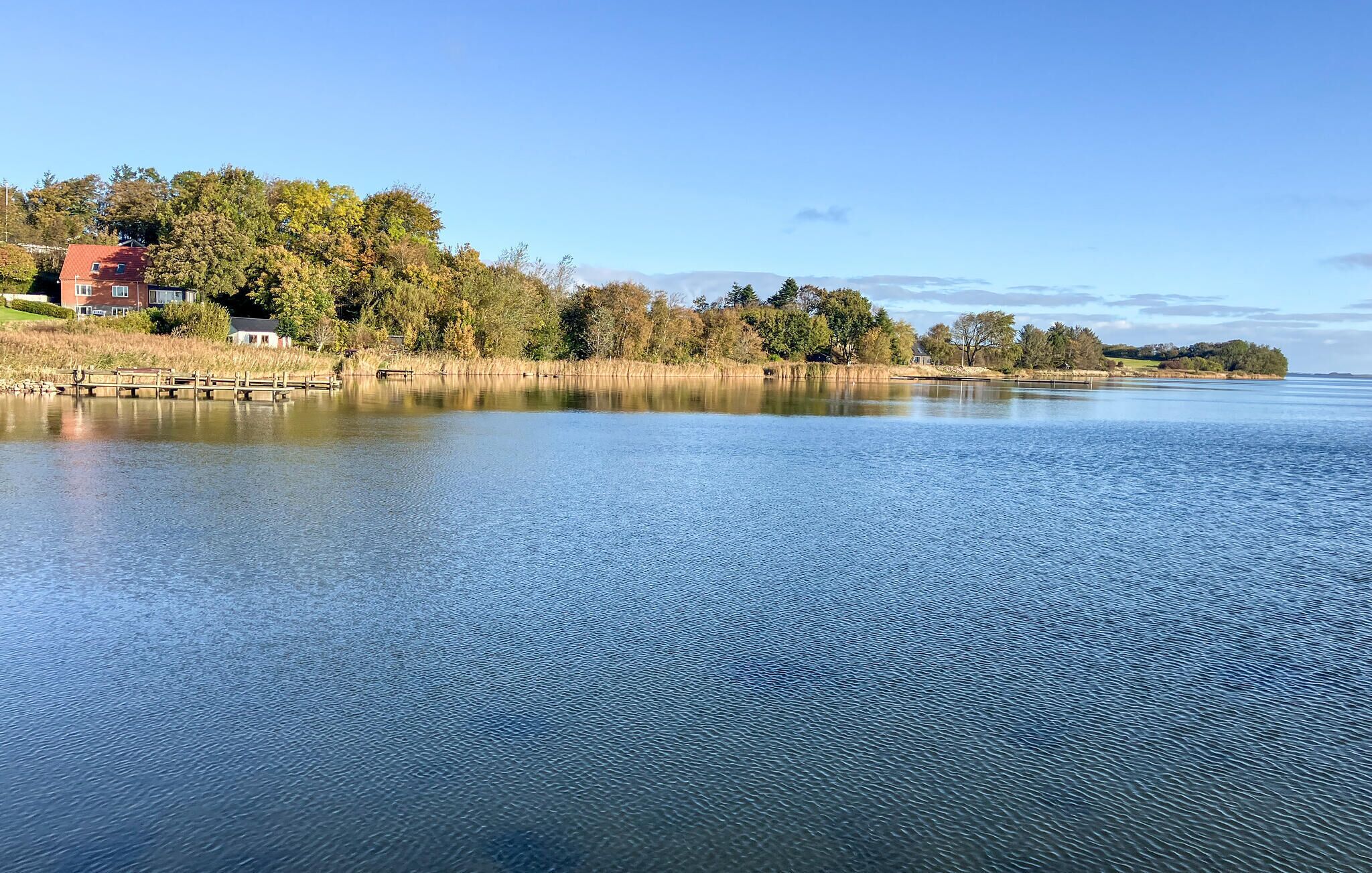 Ein ruhiger See mit einer Holzsteganlage und einer Reihe von Häusern links.