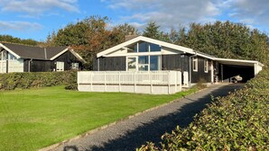 Ein zweistöckiges Haus mit Garage, umzäunter Garten und Schotterweg.