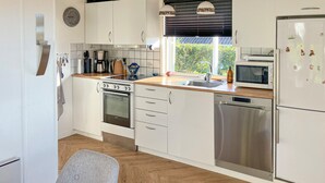 Eine moderne Küche mit weißen Schränken, Edelstahlgeräten und einer Holz Arbeitsplatte.
