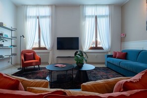 Un salon moderne avec un téléviseur à écran plat, un canapé, un fauteuil, une table basse et une plante.