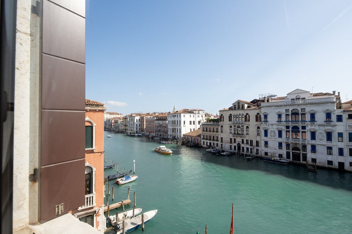 A canal with buildings on either side, boats docked along the water, and a clear sky.
