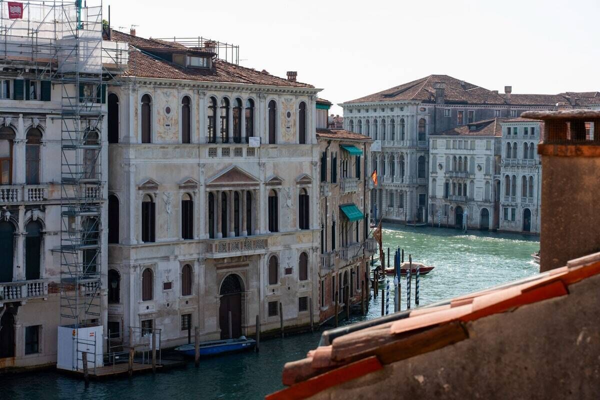 A historic Venetian building with a water canal in the foreground.