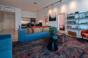 Ein modernes Wohnzimmer mit einem blauen Sofa, einem Couchtisch mit einer Pflanze und einem Bücherregal.