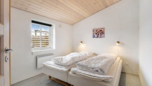 Ein kleines Schlafzimmer mit zwei Betten, einem Fenster mit Blick auf einen Holzzaun und einem 'LOVE'-Schild an der Wand.