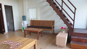 Un salon comprenant un banc en bois, une petite table, un escalier et un distributeur d’eau.