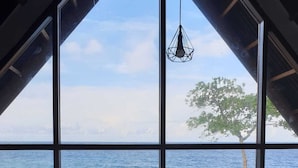 Une pièce dotée d’une grande fenêtre donnant sur une côte rocheuse et la mer.