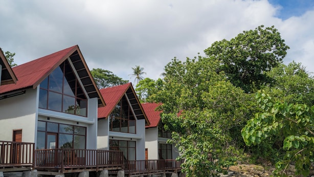 Un hôtel situé en bord de mer, composé de plusieurs bâtiments, doté de grandes fenêtres et d’un toit rouge.