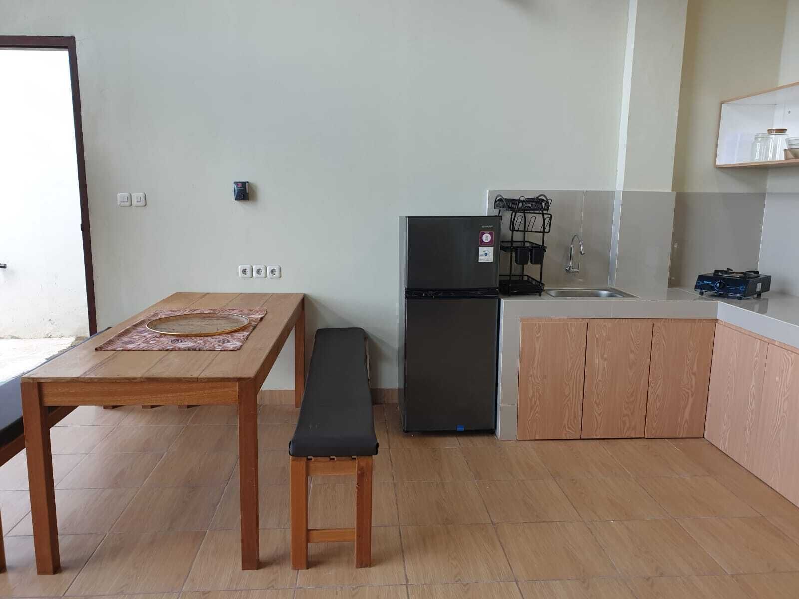 Una cocina compacta con refrigerador, lavamanos y armarios de madera.