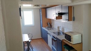 Une cuisine compacte équipée d’un évier, d’une cuisinière, d’un four à micro-ondes et d’un petit coin repas avec une chaise et une table.