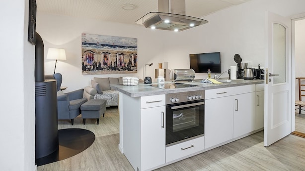 Una cocina moderna con una isla central, horno empotrado y un cuadro grande en la pared.