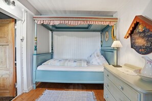 Une pièce comprenant un lit, une commode, une lampe et un élément décoratif mural.