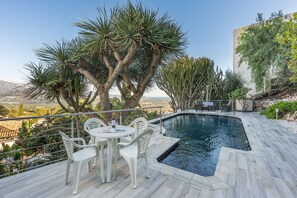 A poolside area with a table and chairs, surrounded by cacti and a view of the landscape. - Villa 'Celeste' with Sea View, Wi-Fi and Air Conditioning (Salobreña (Granada))