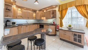 Cozinha com armários de madeira, bancada de granito e área de bar com banquetas.