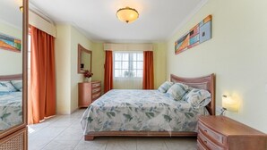 A bedroom with a bed, dresser, mirror, and a window with curtains. - Apartment overlooking heated pool (Santa Cruz de Tenerife)