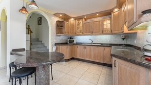 A kitchen with wooden cabinets, a granite countertop, a built-in microwave, and a dining area with a round table and chairs. - Apartment overlooking heated pool (Santa Cruz de Tenerife)
