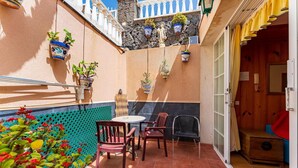 A patio with a table and chairs, potted plants, and a wooden bench.