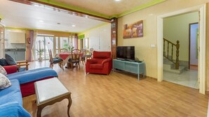 Ein geräumiger Wohnbereich mit einer Küche im Hintergrund, einem Esstisch und einer Treppe, die zu einer weiteren Etage führt.
