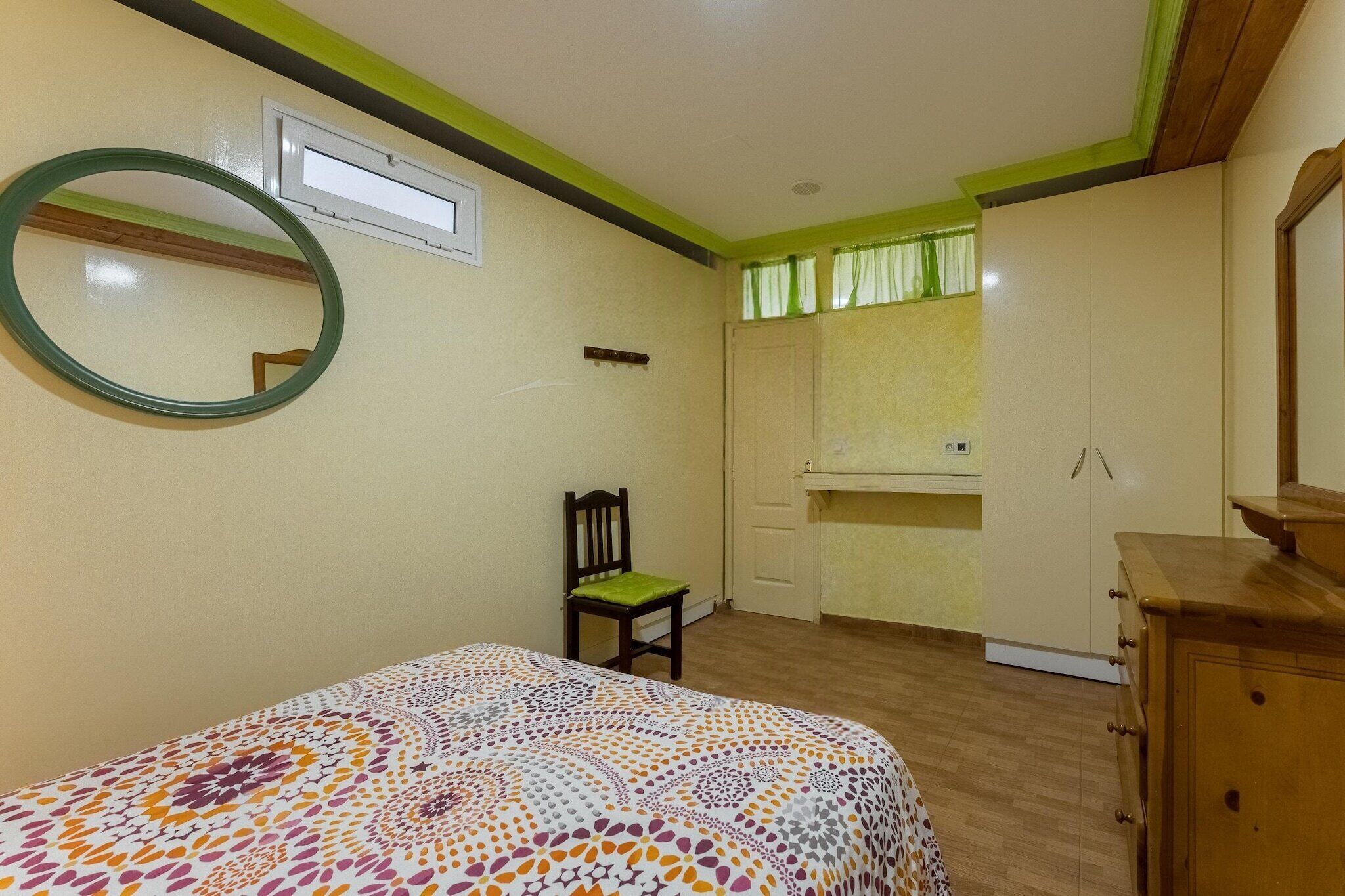 A bedroom with a bed, a chair, a dresser, a mirror, and a wardrobe.