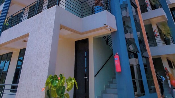 Un edificio moderno de varios pisos con balcones, una escalera y plantas en macetas.