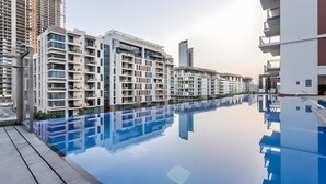 A modern residential building with a reflective pool and balconies. - Studio Near Ras Al Khor Wildlife Sanctuary with Partial Creek Views (Dubai)