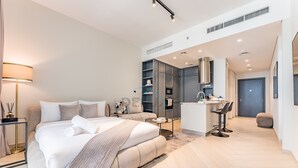 A modern bedroom with a large bed, bedside tables, a desk, and a built-in wardrobe. - Studio Near Ras Al Khor Wildlife Sanctuary with Partial Creek Views (Dubai)