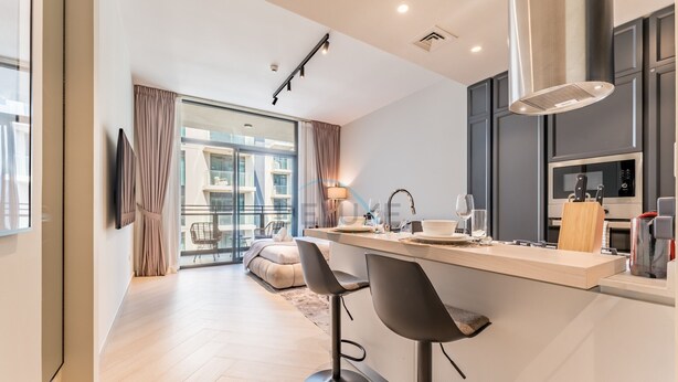 A modern kitchen with a central island, bar stools, and a large window with curtains. - Studio Near Ras Al Khor Wildlife Sanctuary with Partial Creek Views (Dubai)