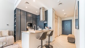 A modern kitchen with a central island, bar stools, and a built-in oven. - Studio Near Ras Al Khor Wildlife Sanctuary with Partial Creek Views (Dubai)