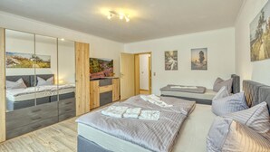 Une chambre moderne avec un grand lit, une armoire, un miroir et un téléviseur.