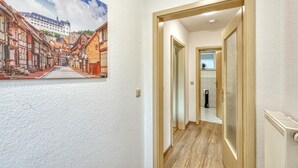 Un couloir orné d’un tableau représentant une scène de rue européenne, doté d’un plancher en bois et d’un radiateur.