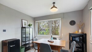 Une cuisine de taille réduite comprenant une table à manger, des chaises, un réfrigérateur, un four à micro-ondes et une horloge murale.